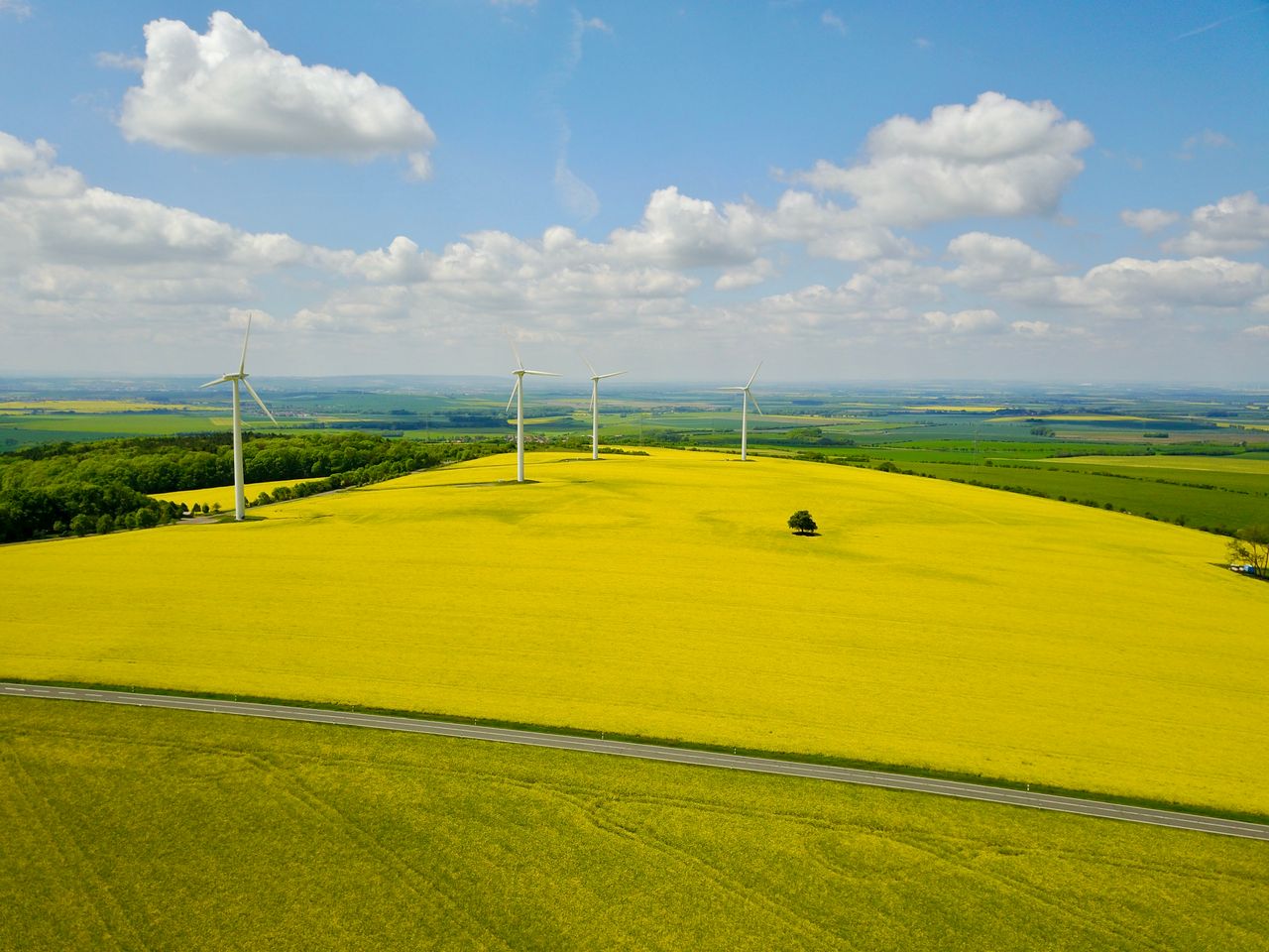 Drone shot of wind turbines over a bright yellow field at Am Ettersberg, Germany.